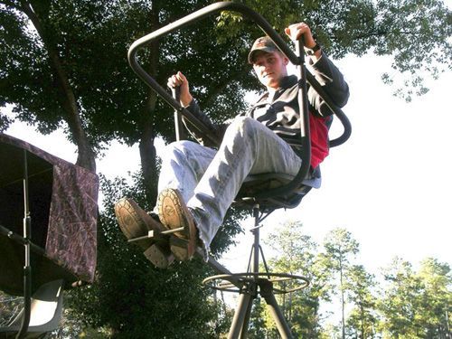 A man is sitting on a swing in the woods
