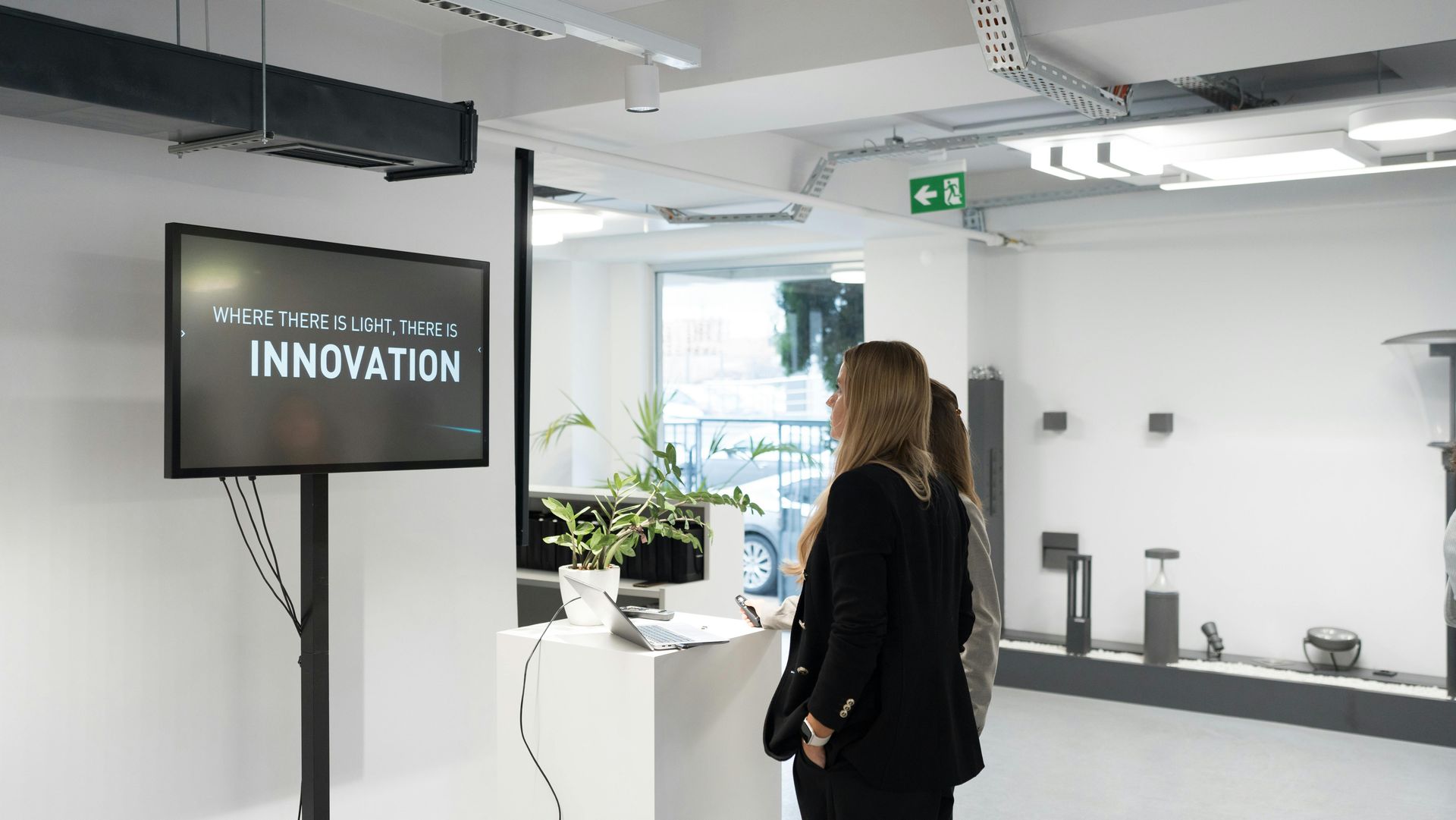 A woman is standing in front of a television that says innovation