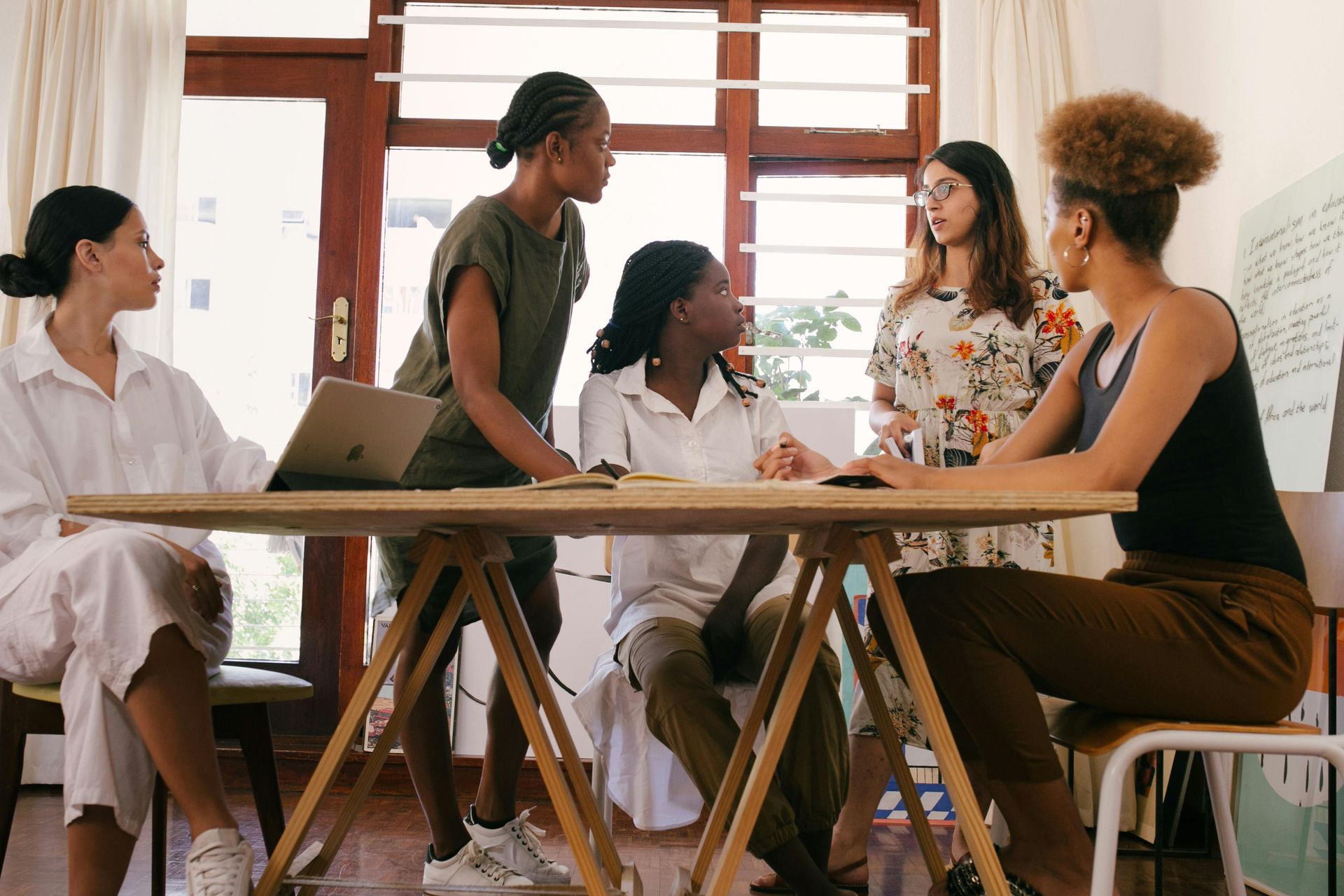 A group of women are sitting around a table having a meeting.