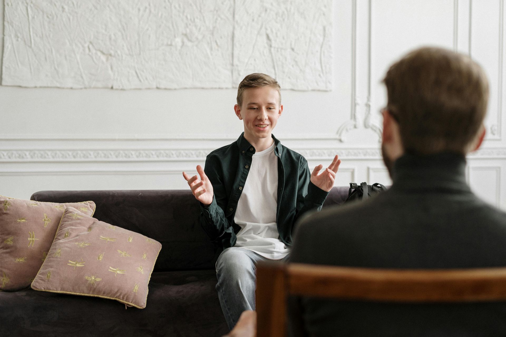 A man is sitting on a couch talking to another man.