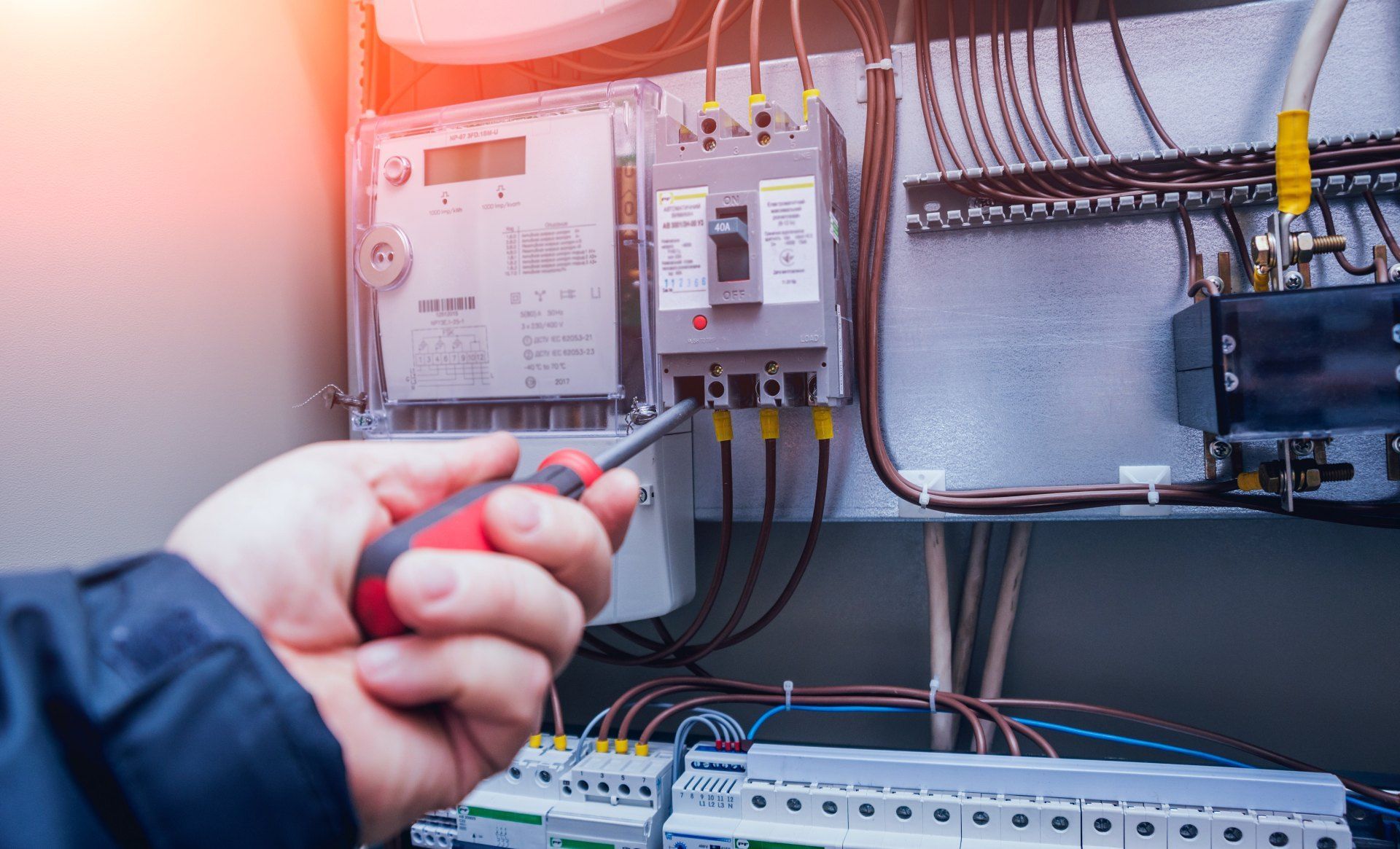 A person is working on an electrical panel with a screwdriver.