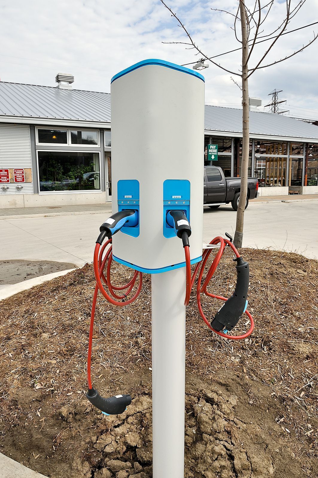 A white pole with two charging stations attached to it.