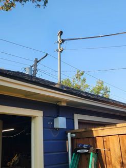 A ladder is sitting on the side of a blue house next to a wooden fence.