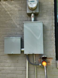 There is a meter on the side of a brick building.