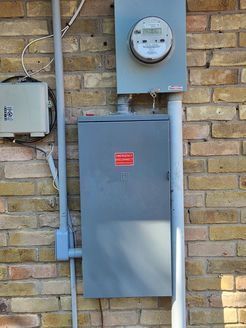 A brick wall with a electrical box and a meter on it.