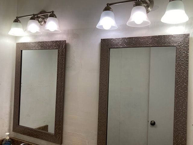 A bathroom with two mirrors and lights on the wall