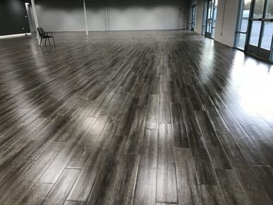 A large empty room with a wooden floor and chairs.