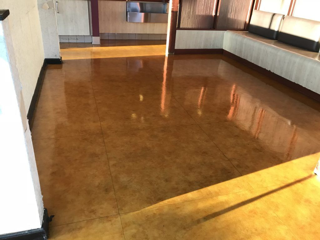 A room with a brown floor and a white wall.