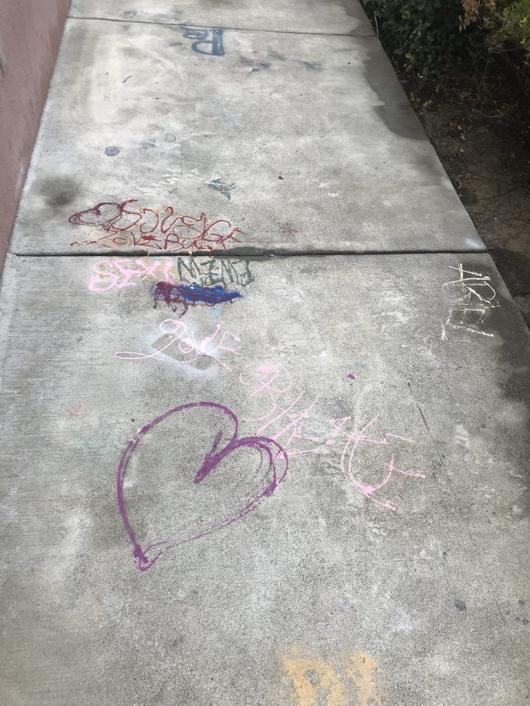 A sidewalk with chalk drawings on it and a heart drawn on it.