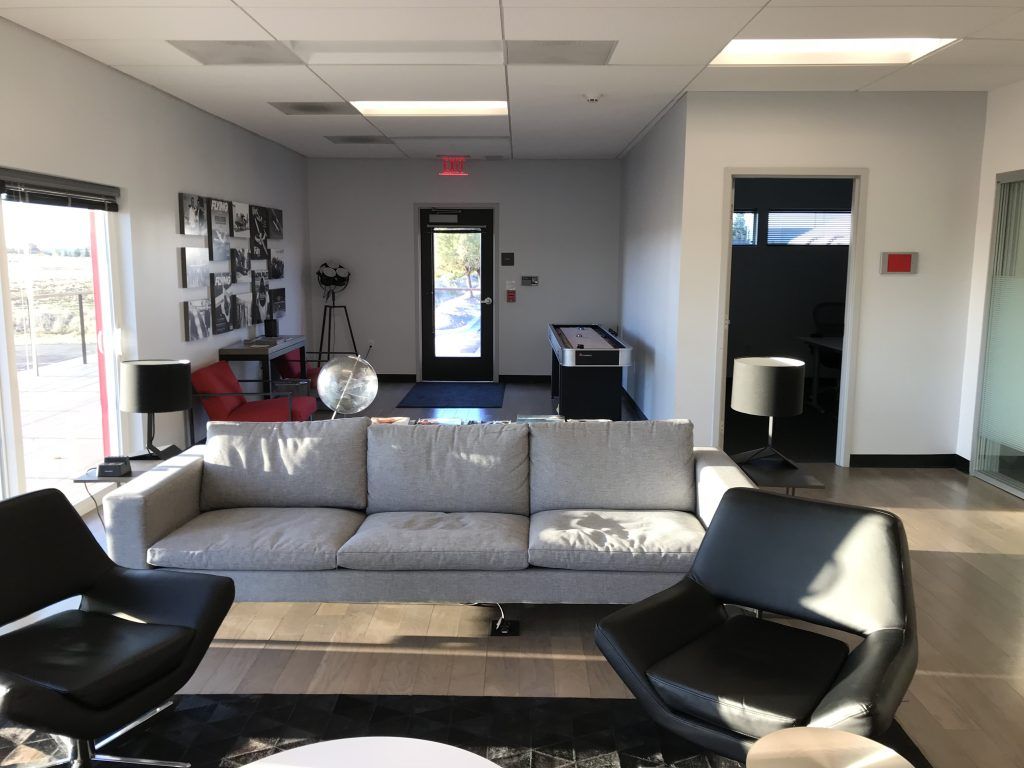 A living room with a couch , chairs and a pool table.