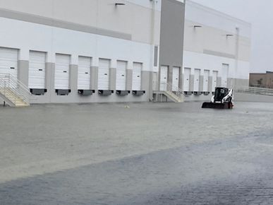 A bobcat is parked in front of a large warehouse