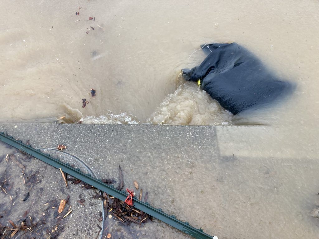 A black bag is floating in a puddle of water.