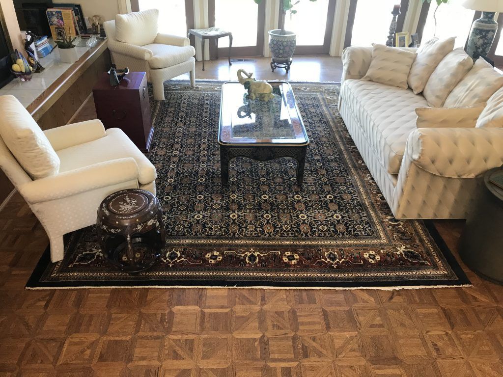 A living room with a couch , chairs , coffee table and rug.