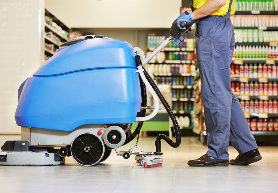 A man is cleaning the floor of a store with a machine.