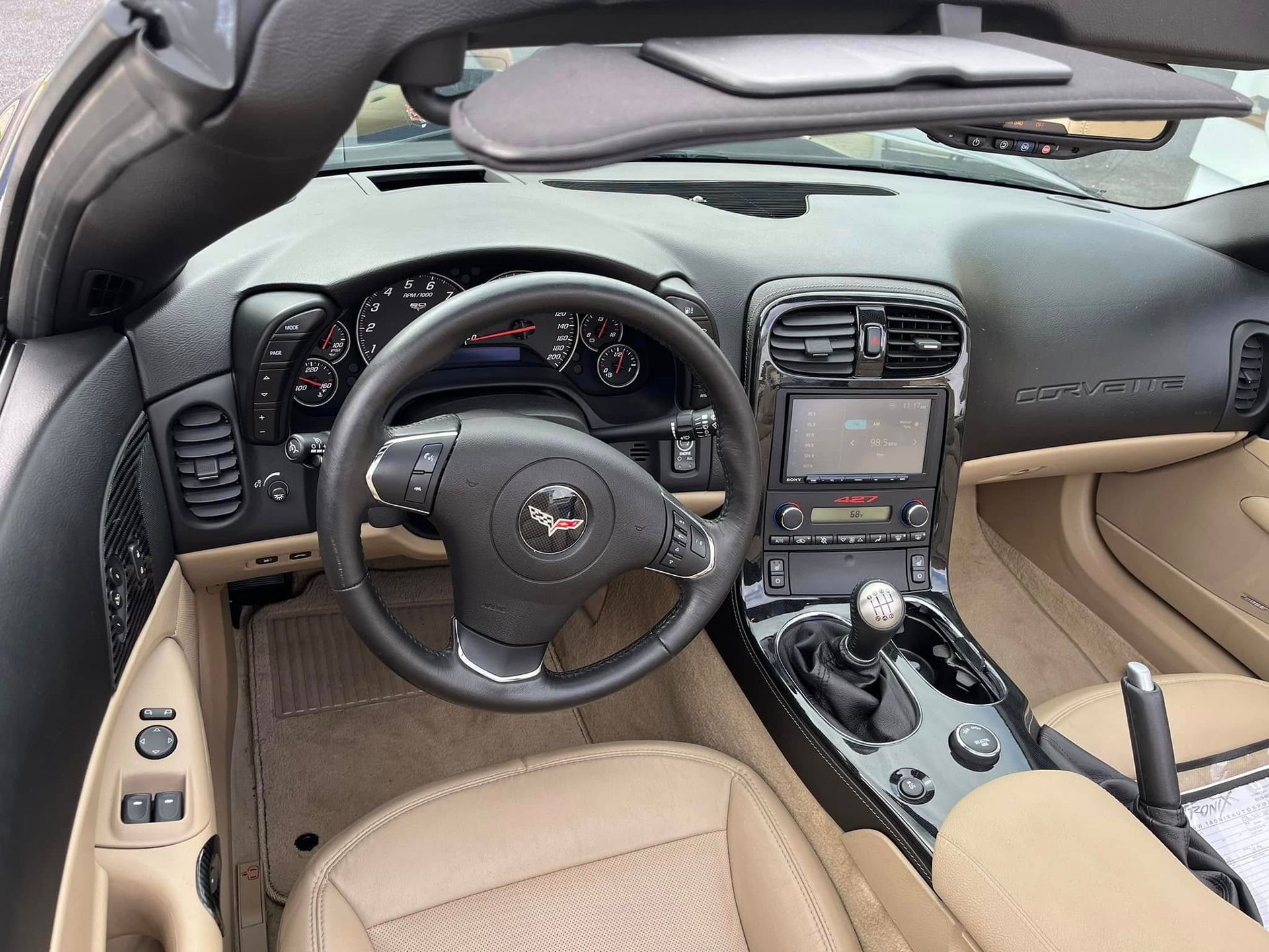 Tan Corvette interior with a black dashboard, steering wheel, and console.