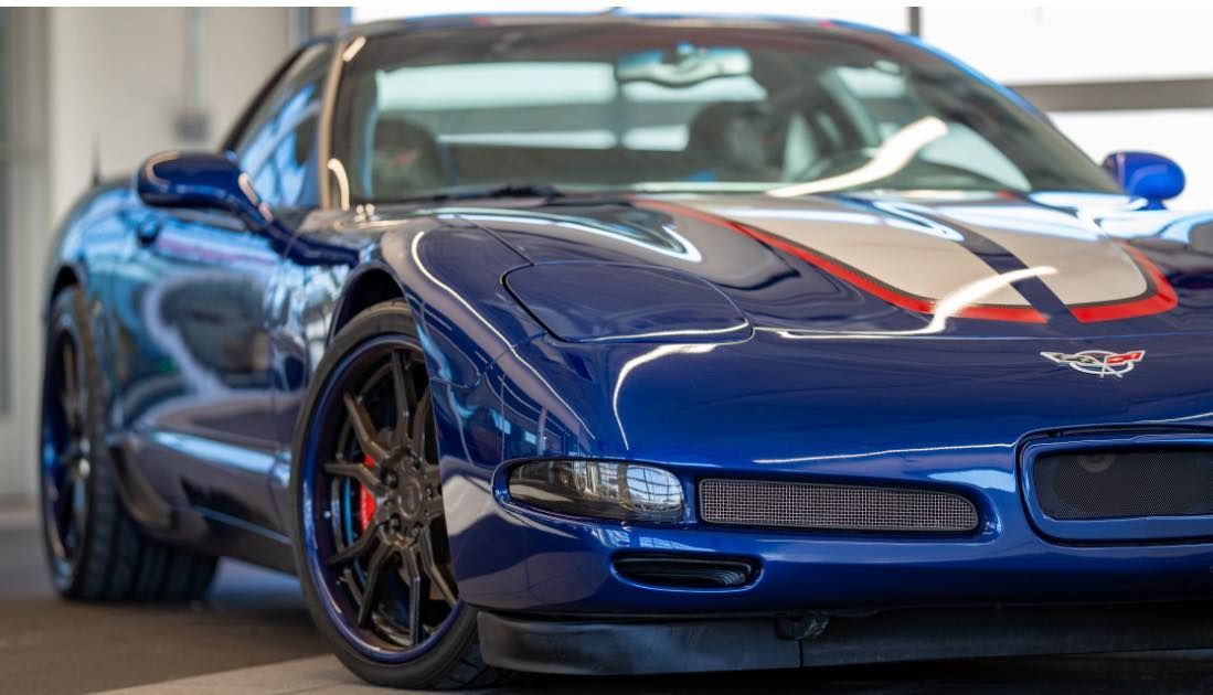 Blue Corvette sports car with white and red stripes on the hood, black wheels.