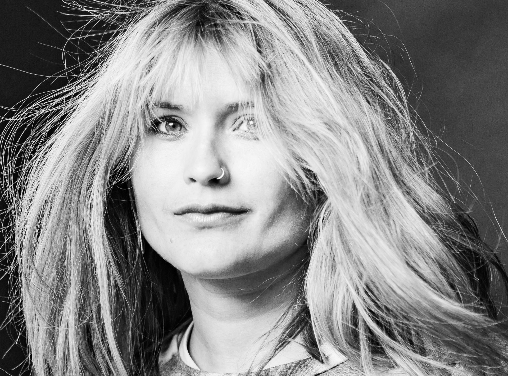 Schwarzweißfoto Porträt einer Frau mit langen blonden Haaren und startem Ausdruck