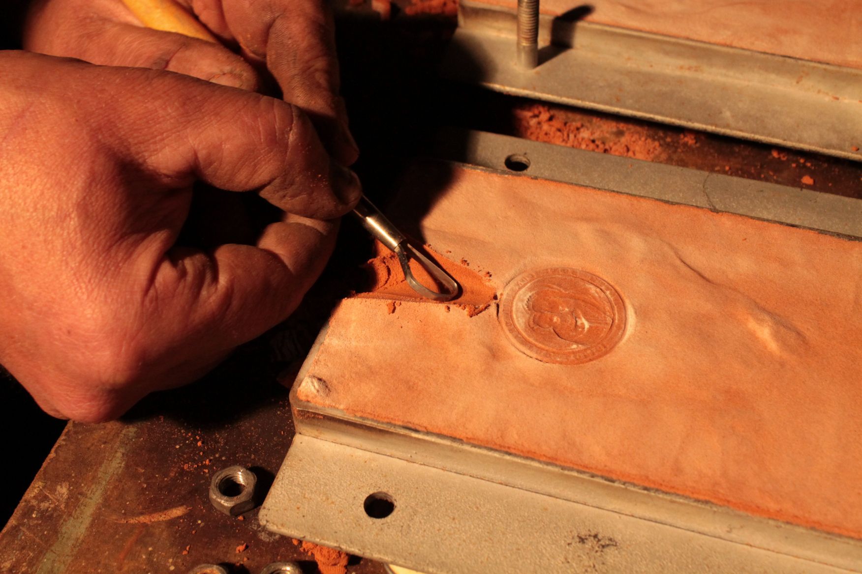 Eine Person bearbeitet ein Stück Leder mit einem Werkzeug