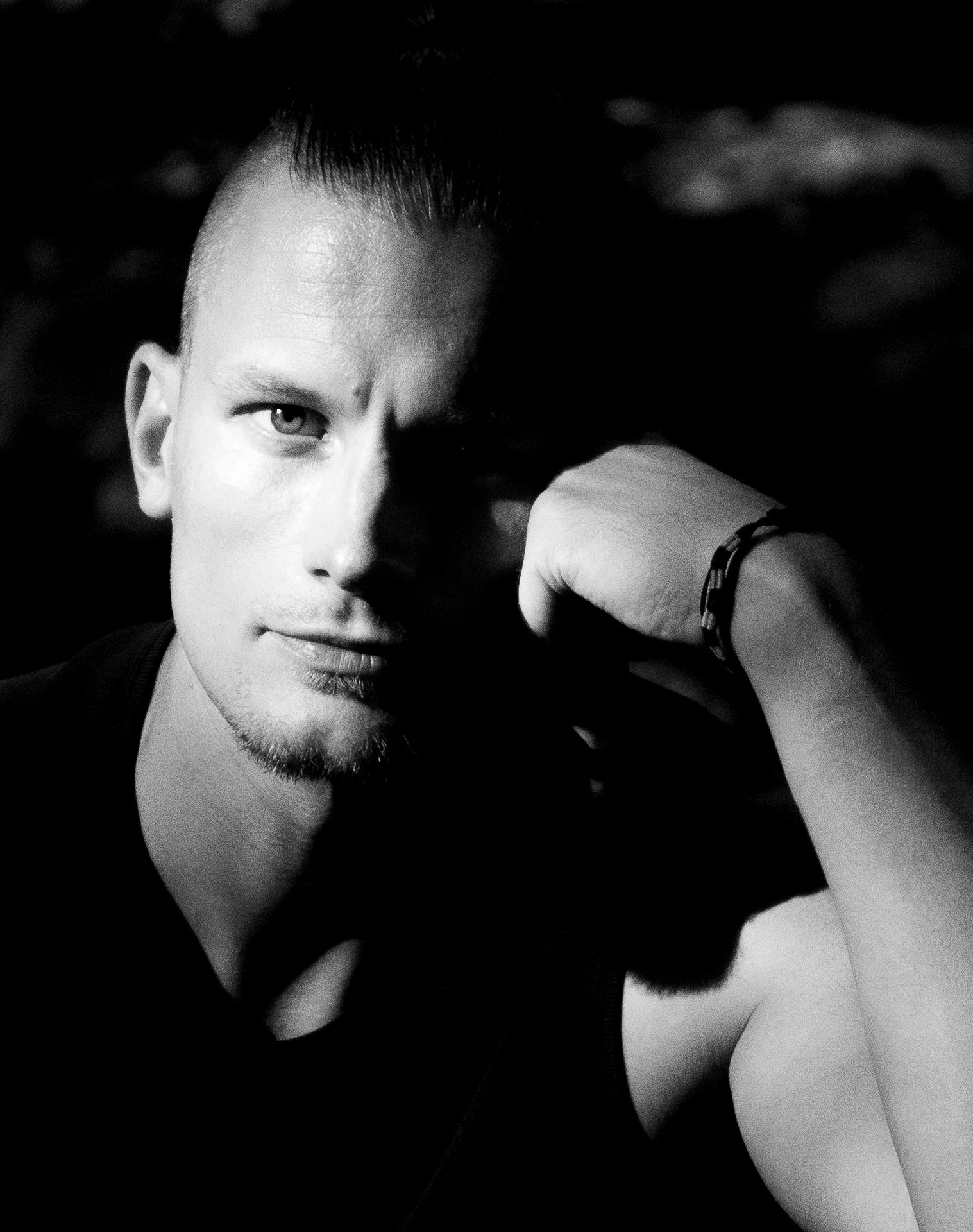 Schwarzweißfoto Porträt eines Mannes mit Seitenlicht der konzentriert ernst in die Kamera schaut