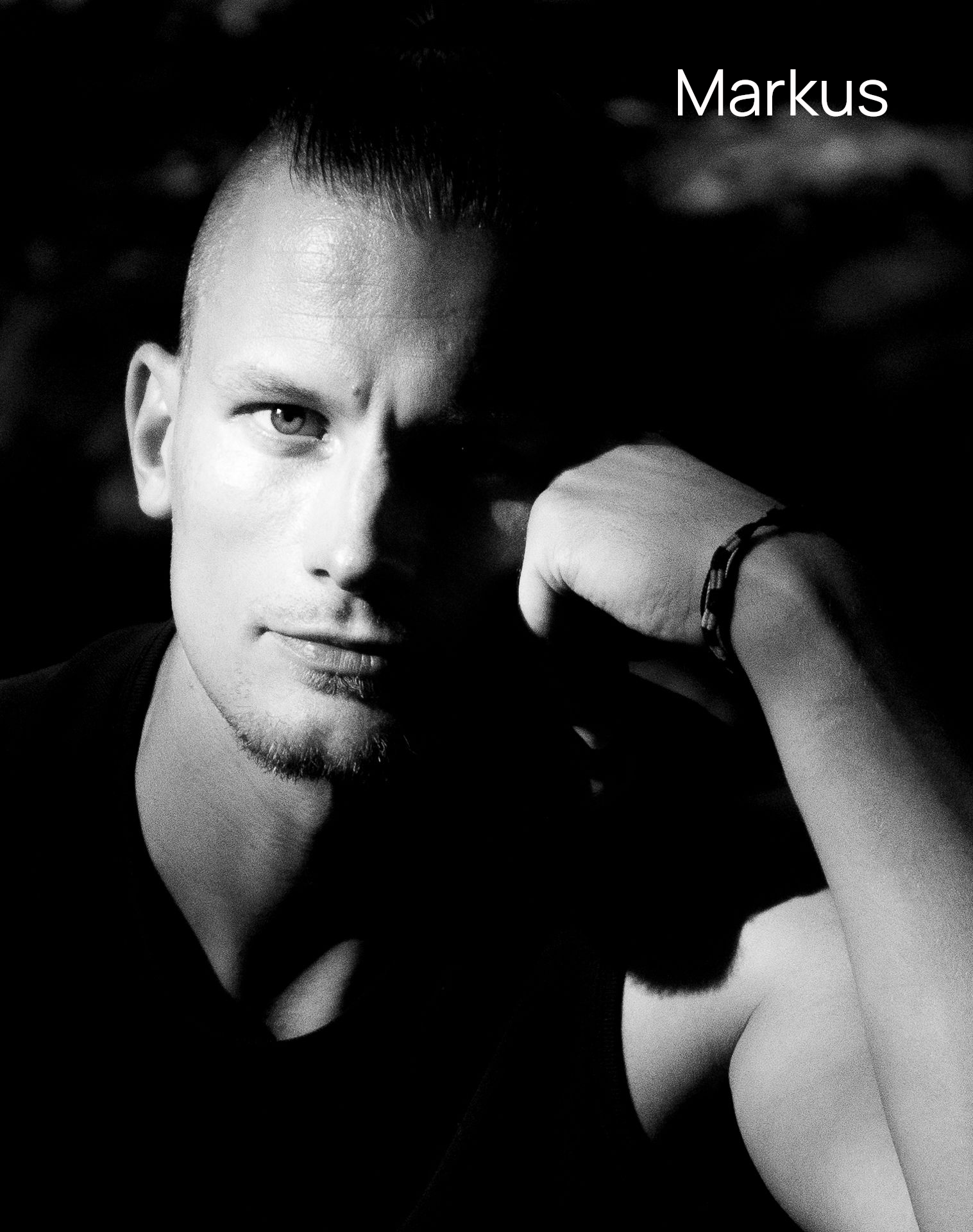 Schwarzweißfoto Porträt eines Mannes mit Seitenlicht der konzentriert ernst in die Kamera schaut