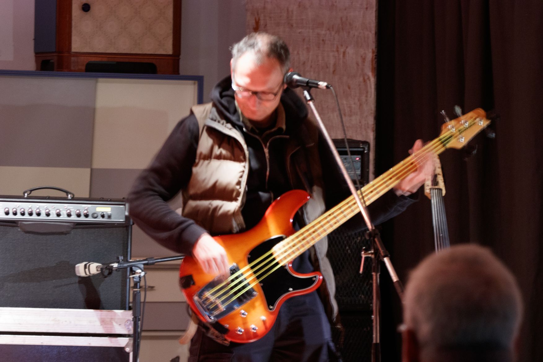 Ein Mann spielt Bassgitarre und singt in ein Mikrofon