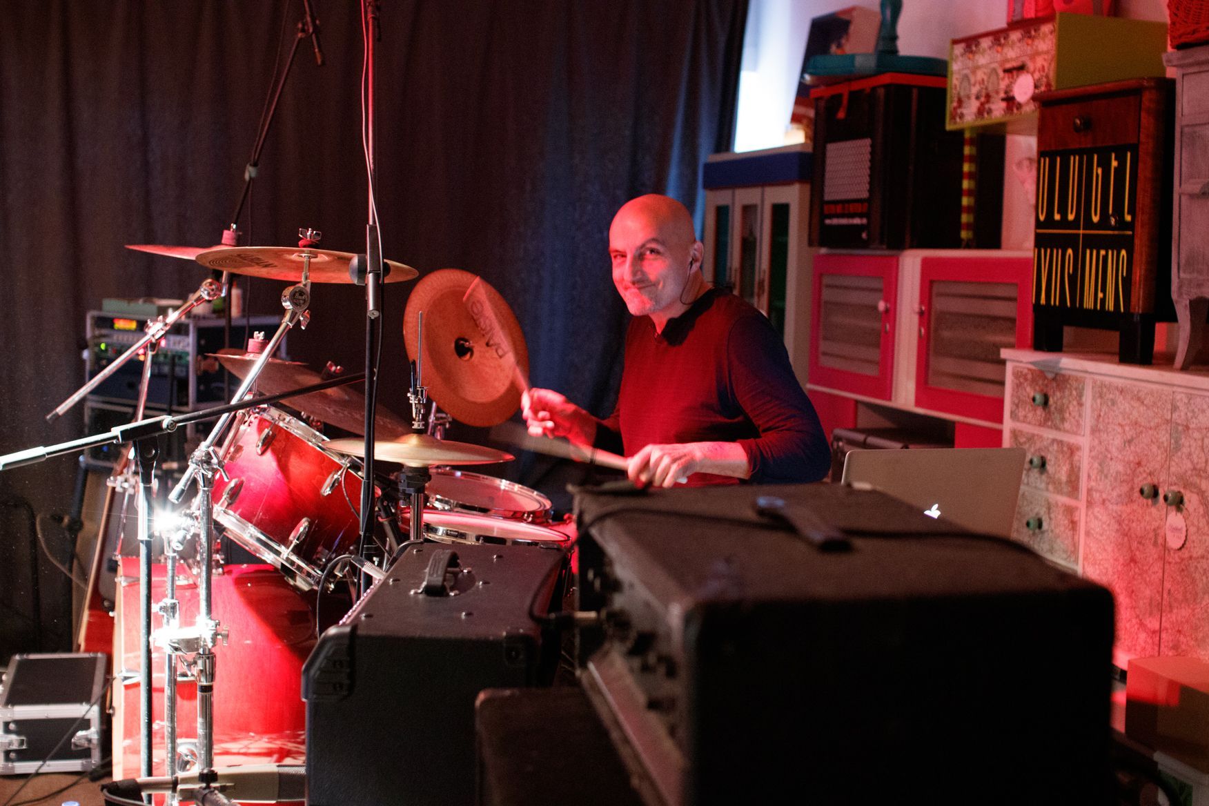 Ein kahlköpfiger Mann spielt Schlagzeug in einem dunklen Raum