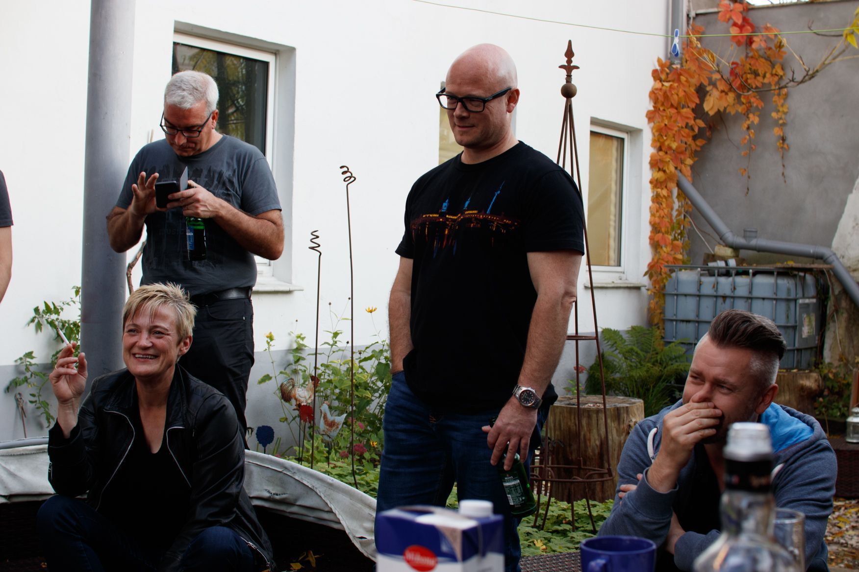 Eine Gruppe von Menschen hat sich draußen versammelt, darunter ein Mann mit Brille