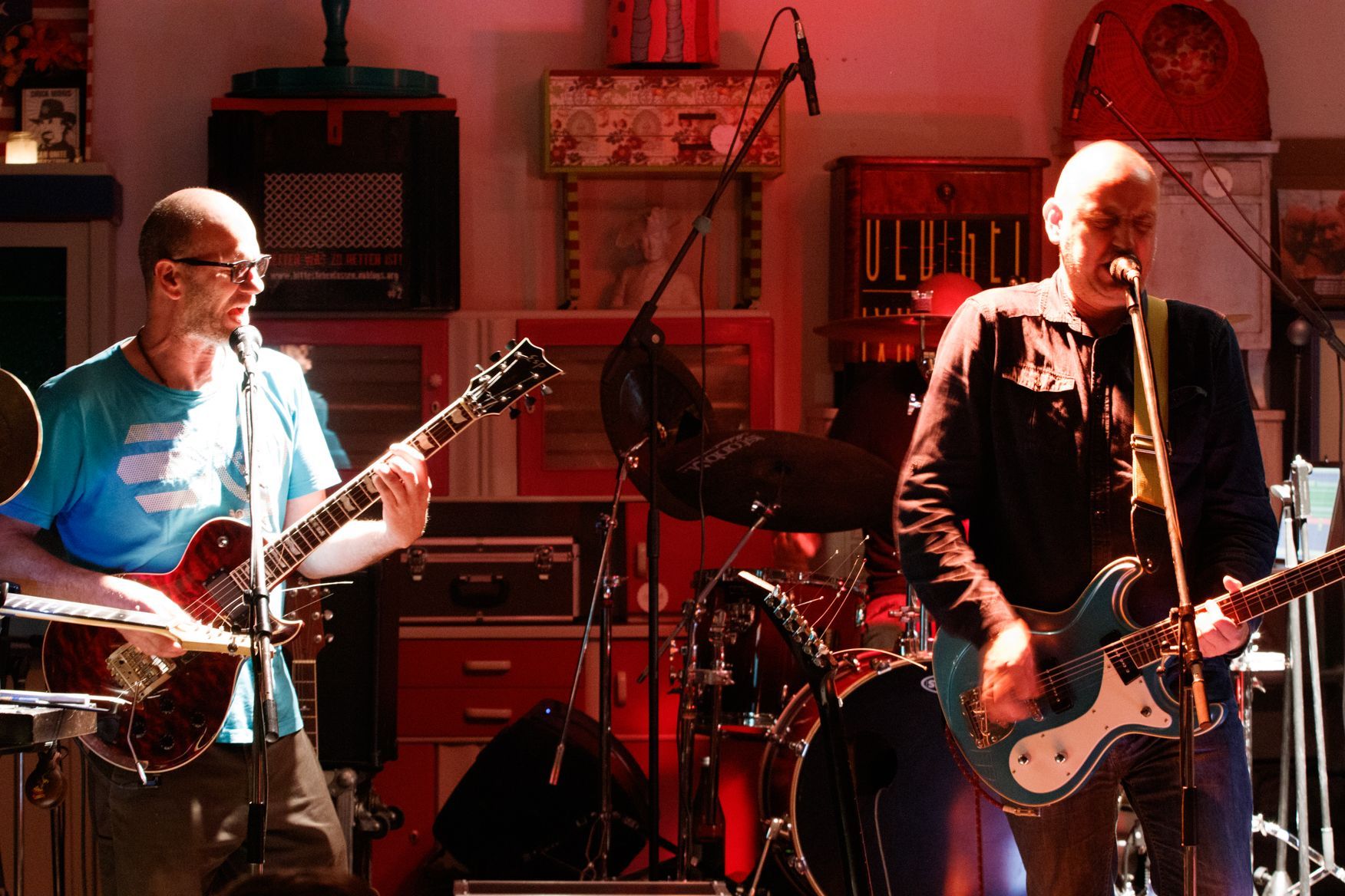 Ein Mann, der in ein Mikrofon singt, während ein anderer Mann Gitarre spielt