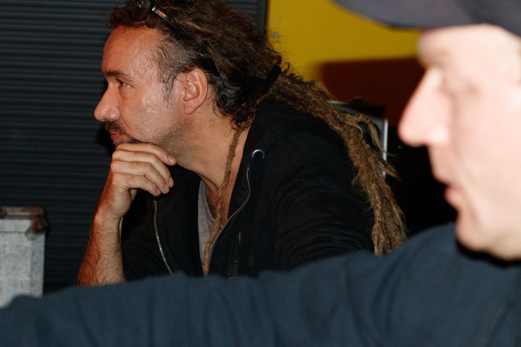 Ein Mann mit Dreadlocks sitzt mit einem anderen Mann in einem dunklen Raum