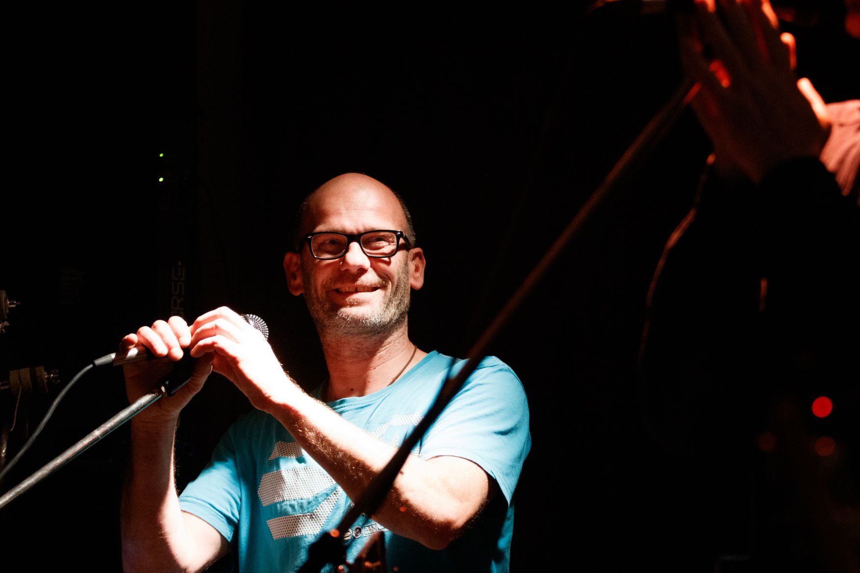 Ein Mann in einem blauen Hemd singt in ein Mikrofon