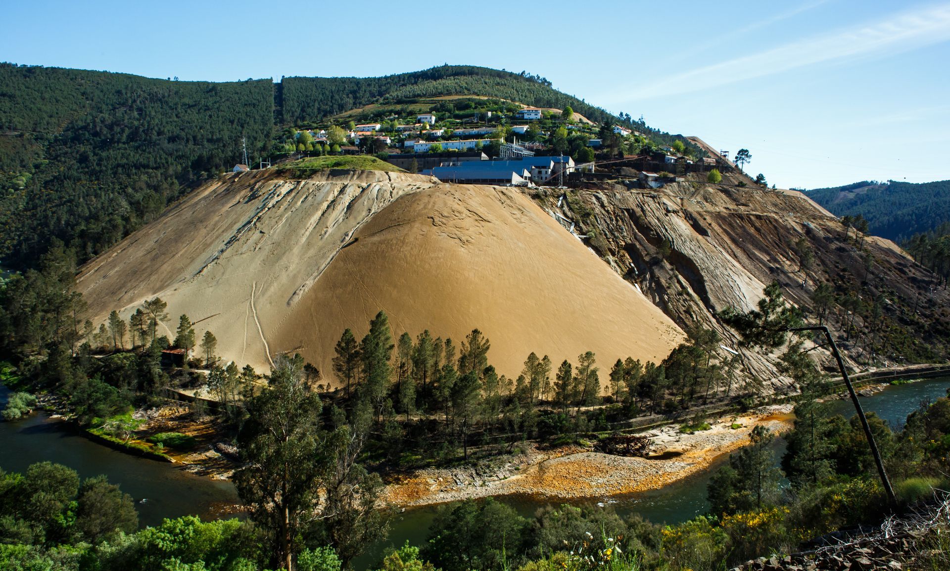 Ein großer Erdhügel ist von Bäumen und einem Gewässer umgeben