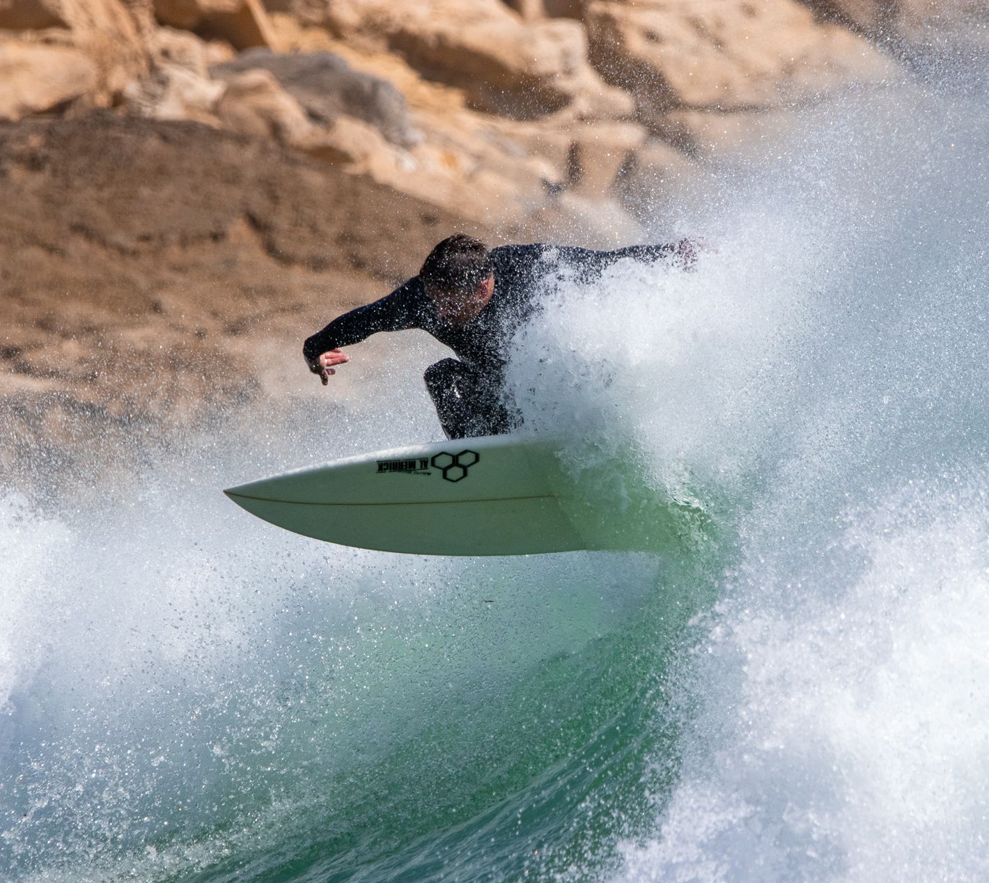 Eine Surfer, der auf einem Surfbrett eine Welle reitet an der Algarve in Portugal