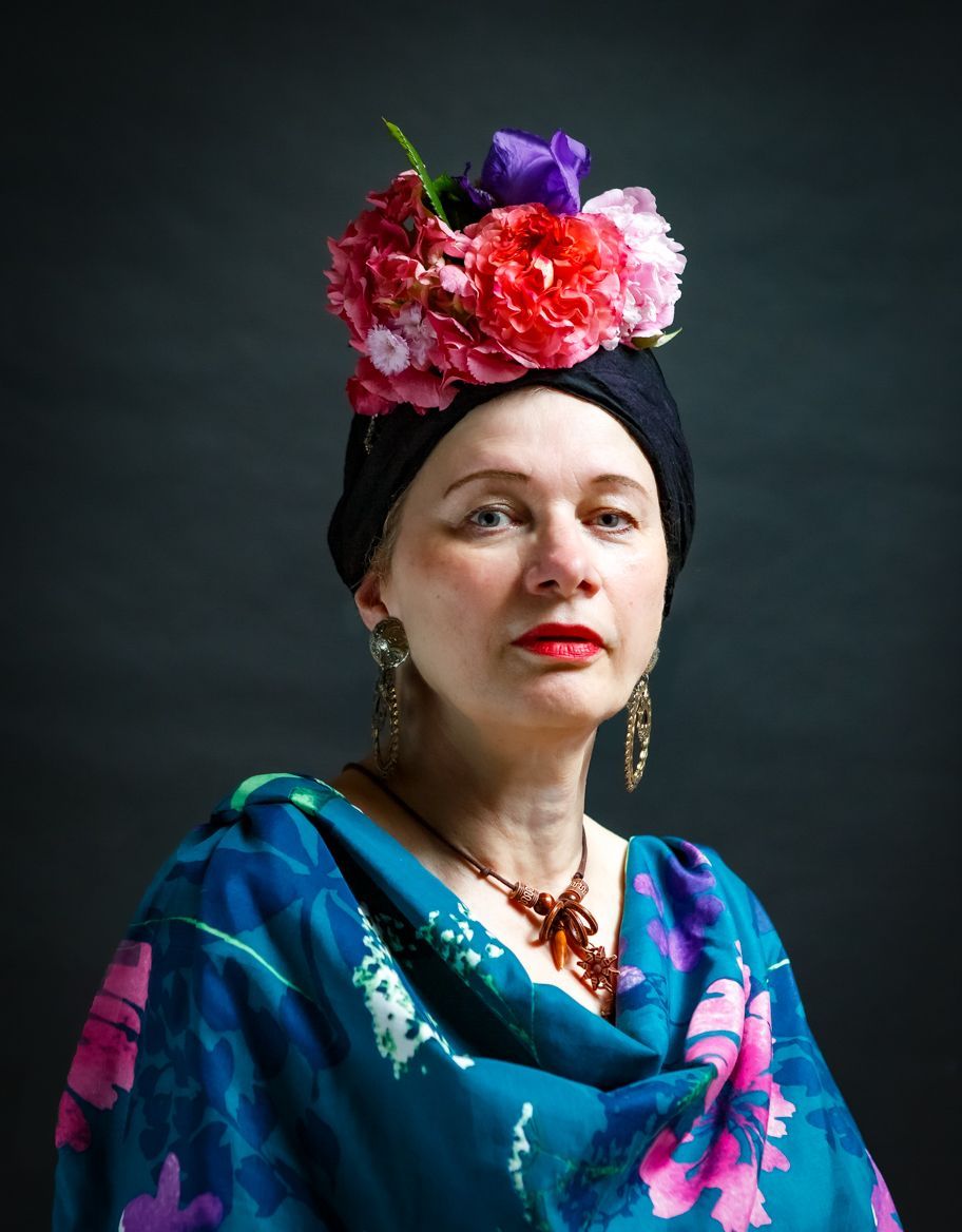 Konzeptionelle Fotografie einer Frau mit afrikanischem Look, Blumen in den Haaren und mit Blumen gemusterter Bluse