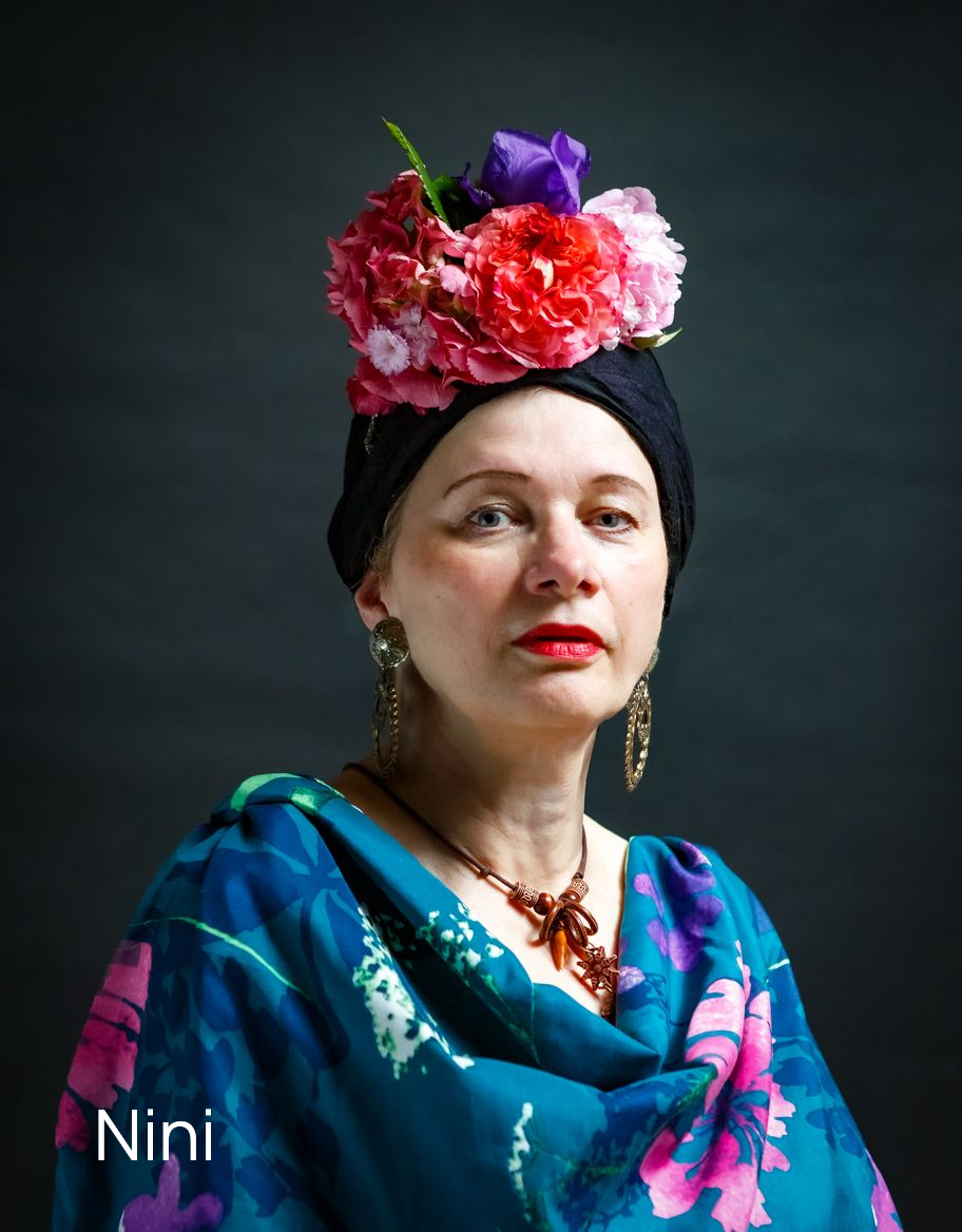 Konzeptionelle Fotografie einer Frau mit afrikanischem Look, Blumen in den Haaren und mit Blumen gemusterter Bluse