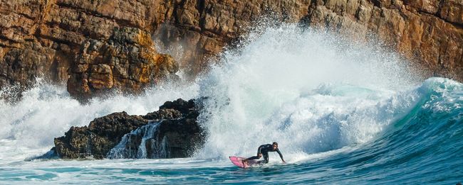 Robert Liedtke Photo Squad 711 Ein Surfer reitet auf einem pinkfarbenem Surfbrett auf einer Welle an der Algarve in Ingrina Portugal