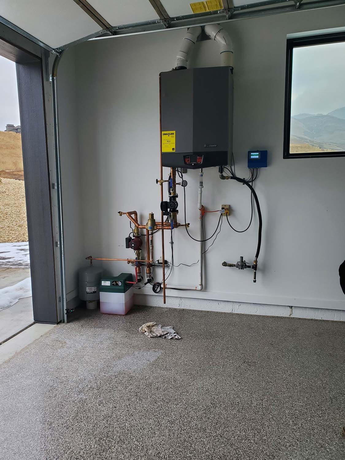 A water heater system installed in a garage with copper pipes and a digital control panel.