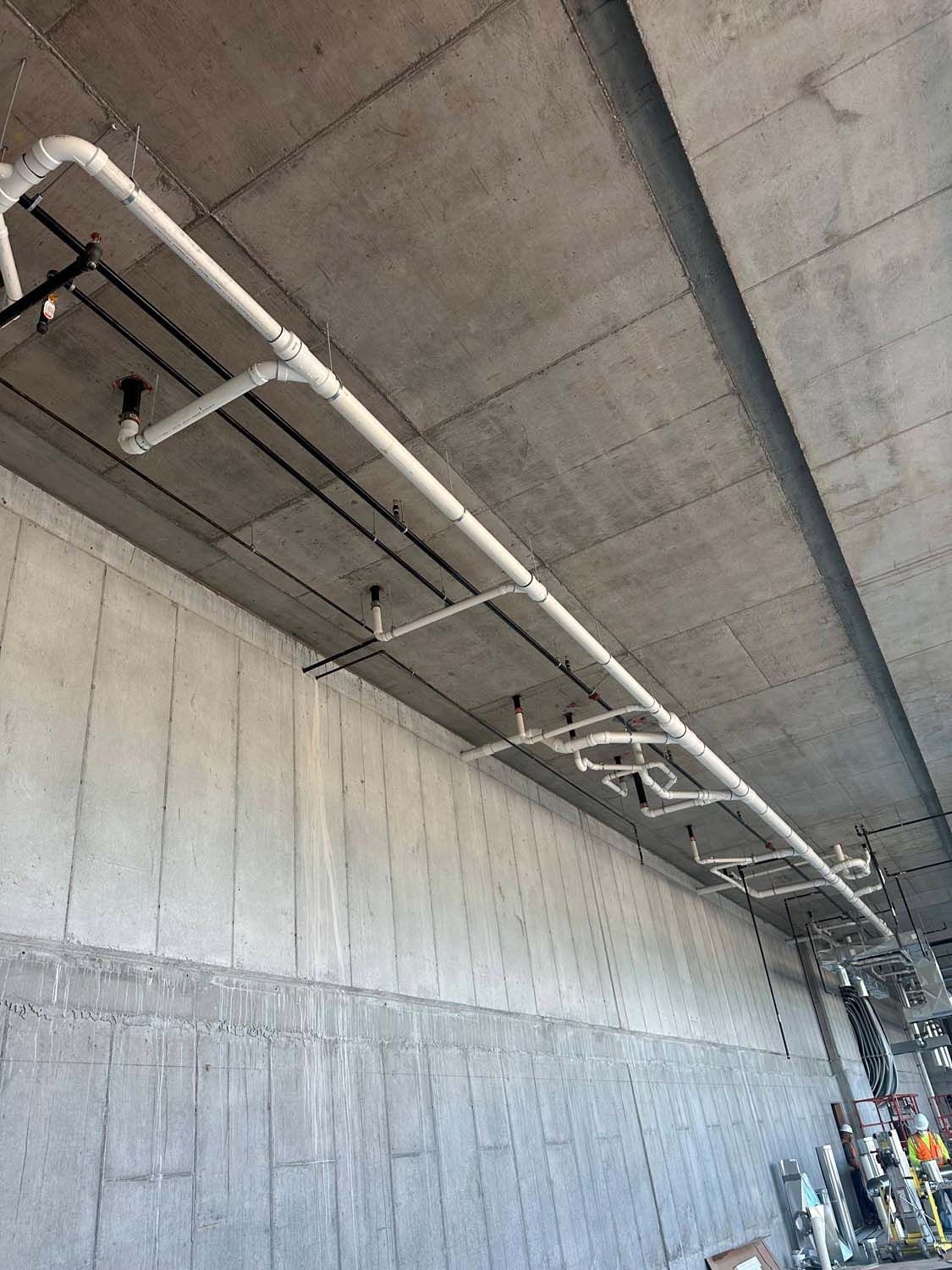 White pipes installed on a concrete ceiling, likely for a building's systems.