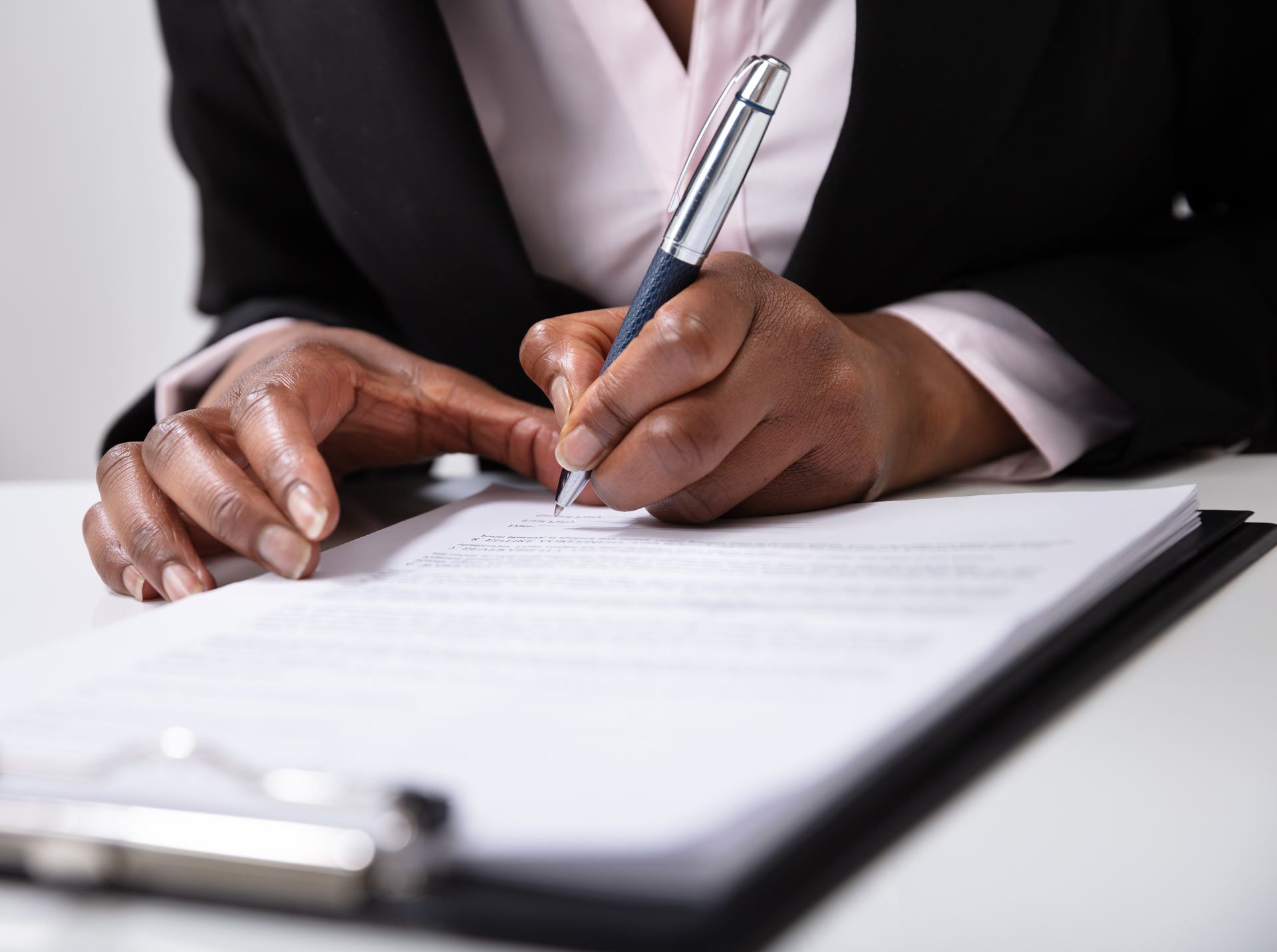 A woman is writing on a piece of paper with a pen.