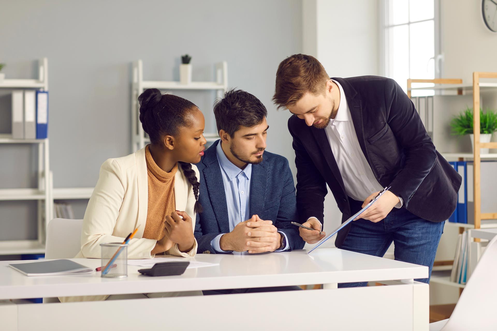 A group of people are sitting at a table in an office looking at a piece of paper