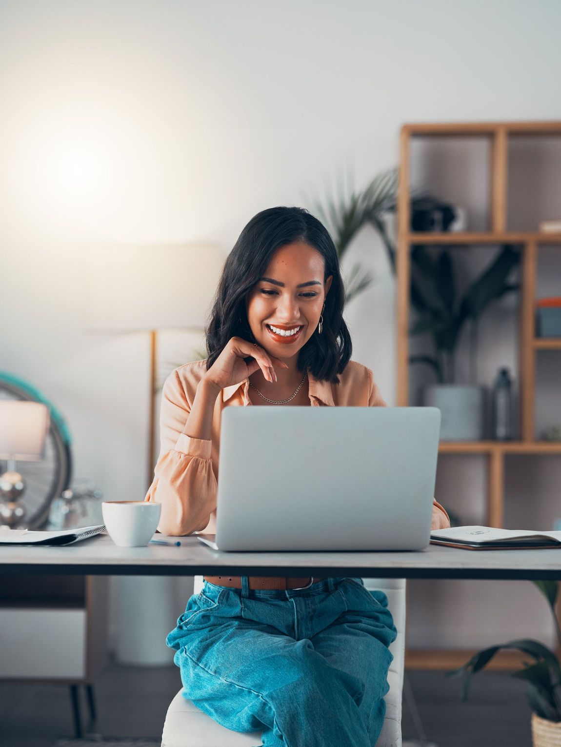 A woman is sitting at a desk using a laptop computer.