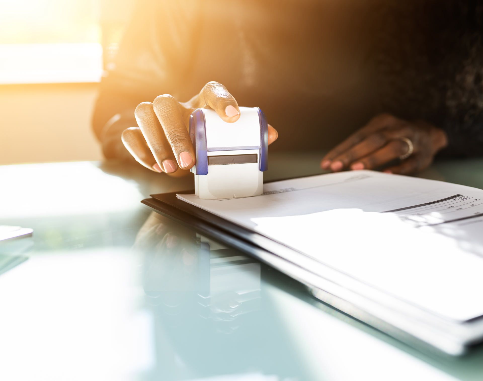 A woman is holding a stamp over a piece of paper.
