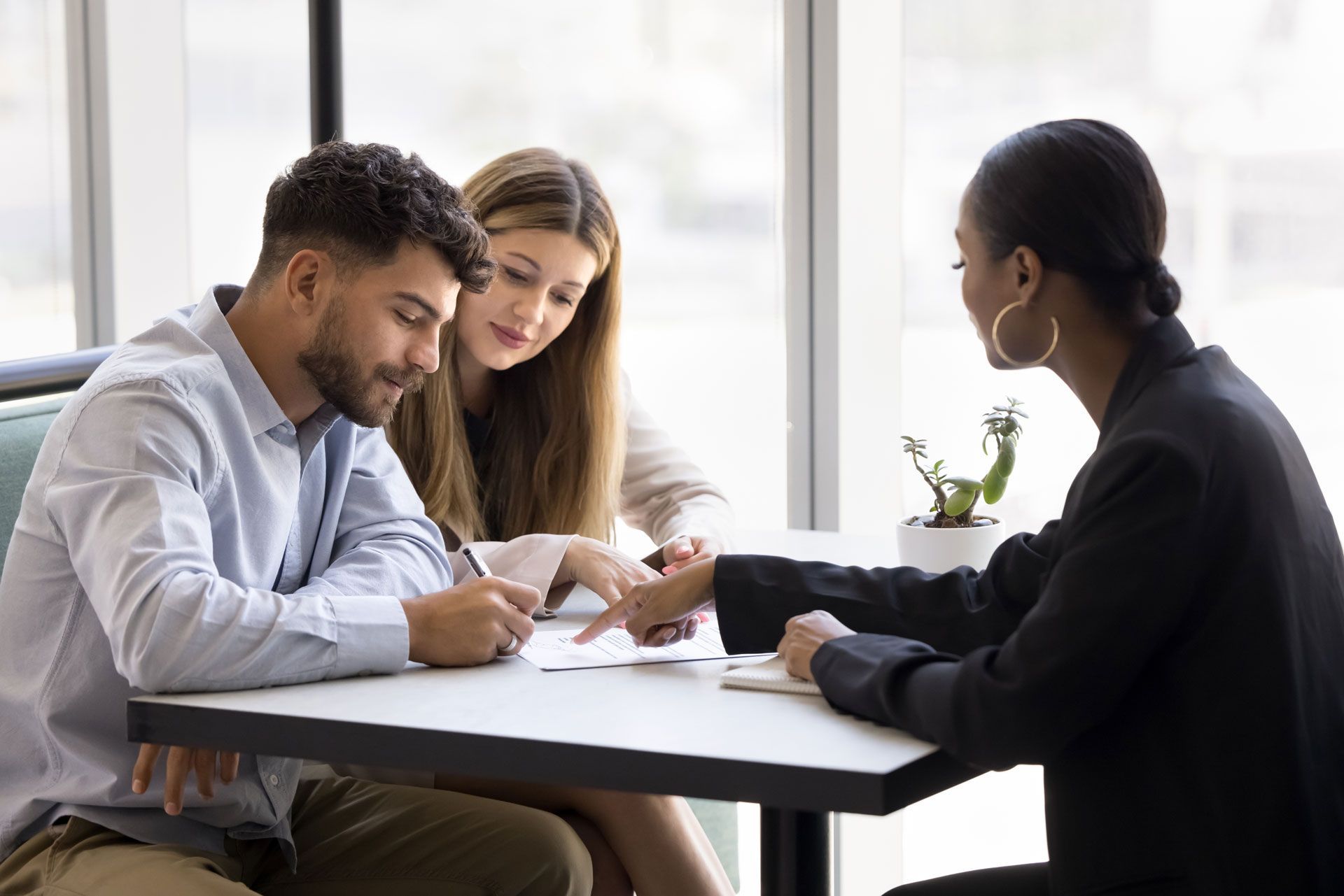 A man and a woman are sitting at a table signing a document.