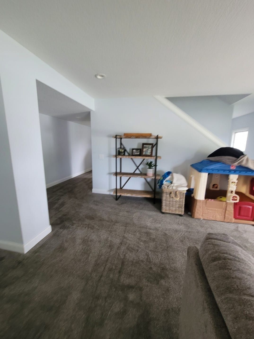 A living room with a couch , bookshelf , and playhouse.