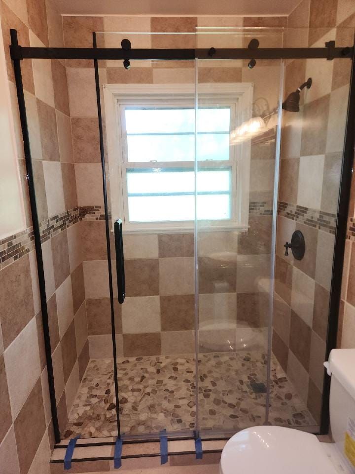 A bathroom with a sliding glass shower door and a toilet.