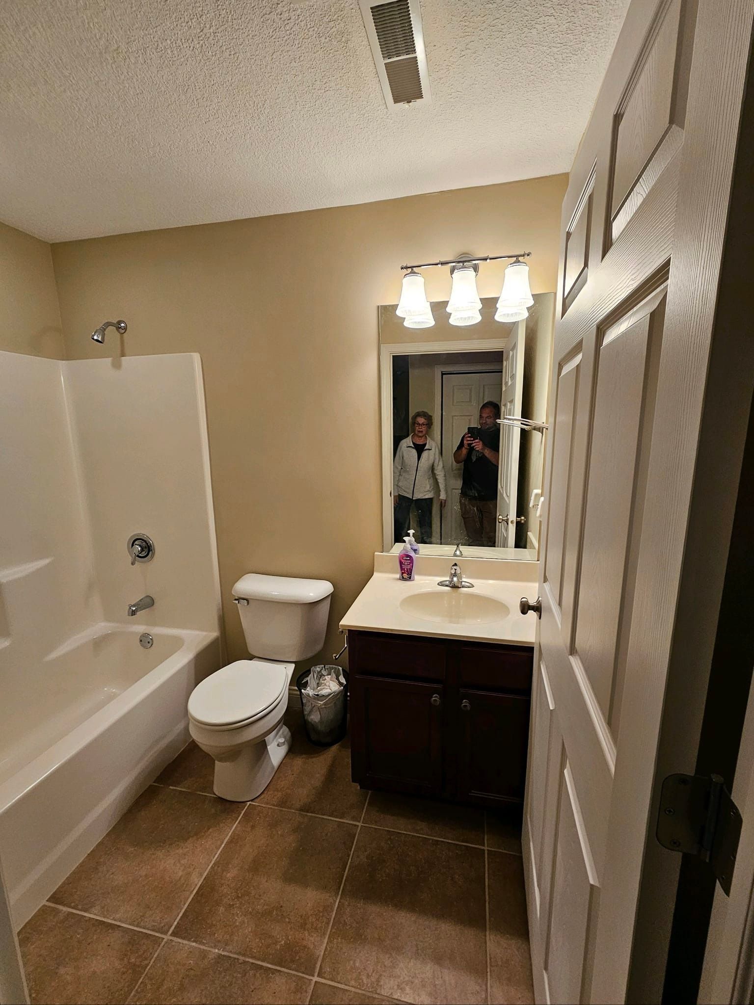 A bathroom with a toilet , sink , bathtub and mirror.