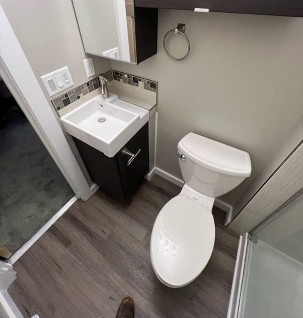 A bathroom with a toilet , sink and mirror.