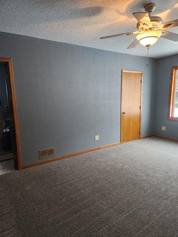 An empty room with a ceiling fan and a door.