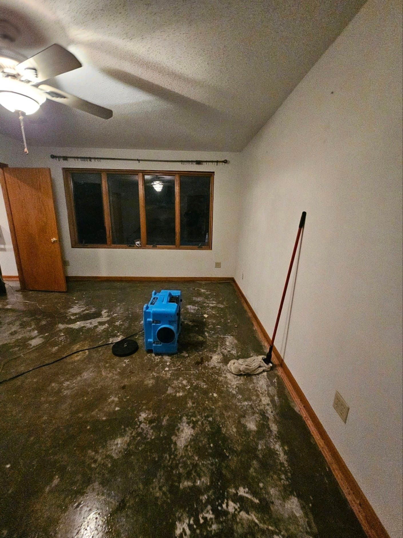 A room with a ceiling fan and a mop on the floor.