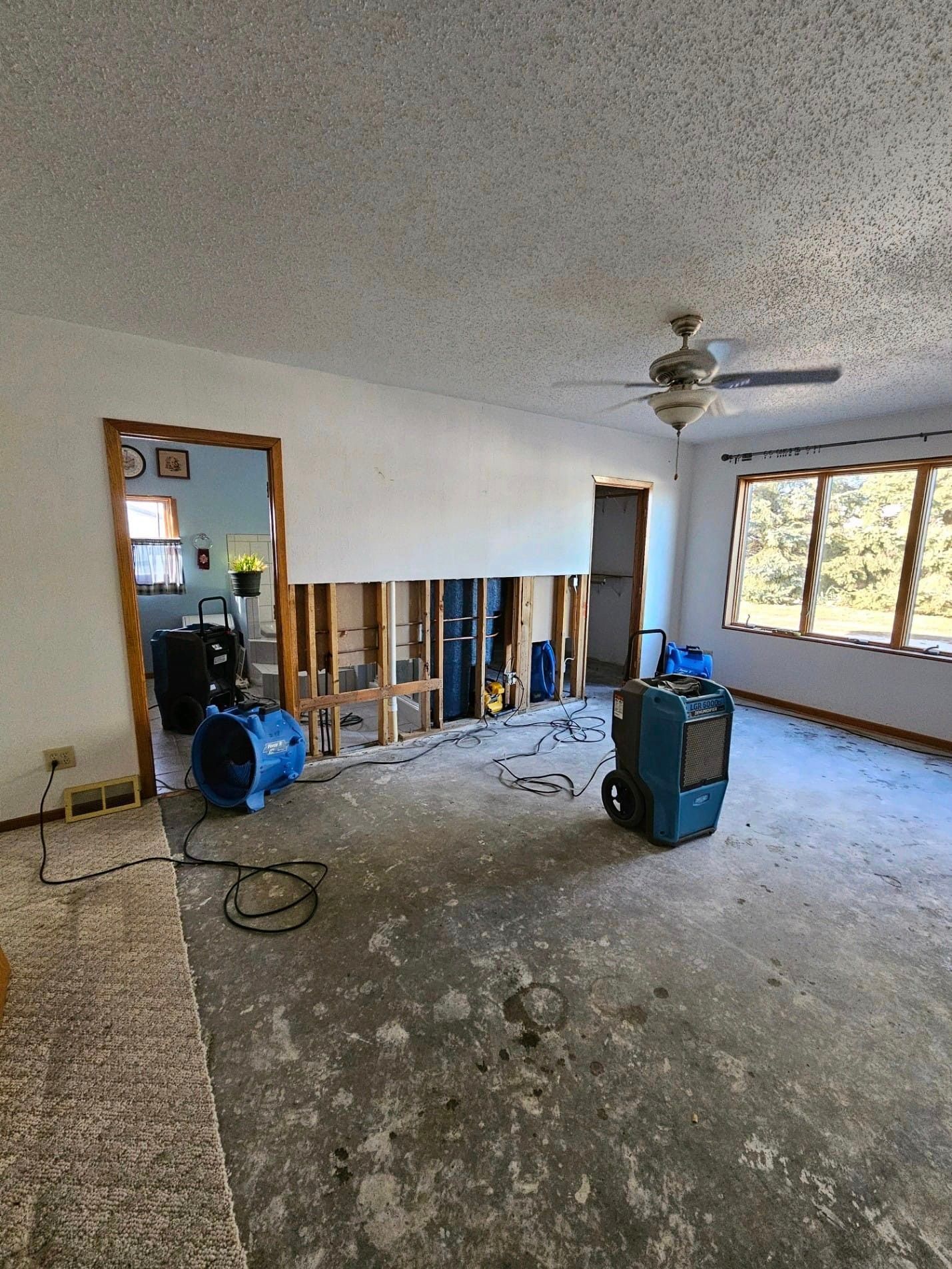 A living room with a ceiling fan and a machine on the floor.