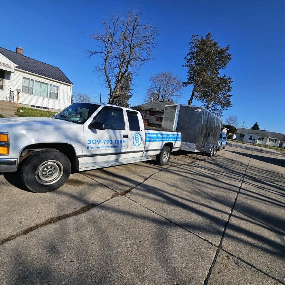 A white truck is parked on the side of the road with a trailer attached to it.